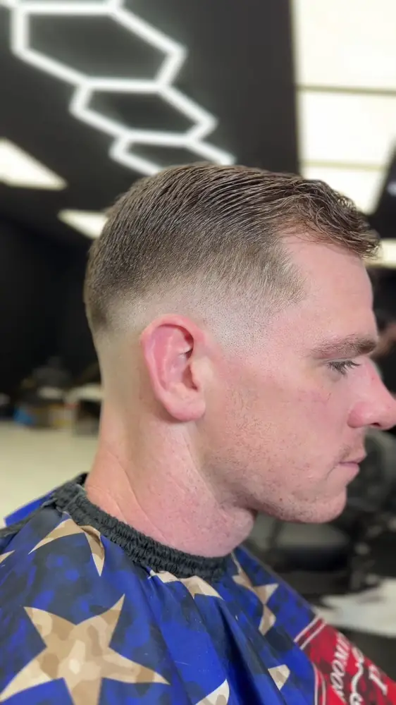 Fresh skin fade with a side-swept top, under the hexagon lights at Axis Cuts
